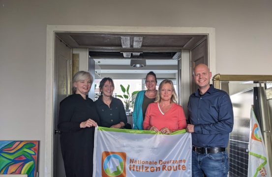 Foto van Ariane, wethouder Zeegers en anderen met vlag Duurzame Huizenroute