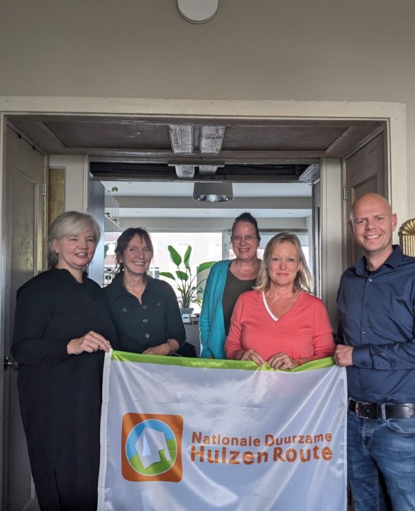 Foto van Ariane, wethouder Zeegers en anderen met vlag Duurzame Huizenroute